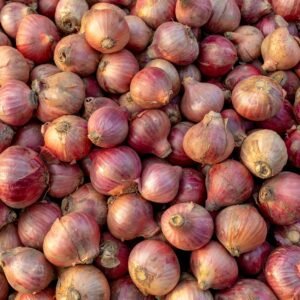 Close-up of numerous red onions piled together showcasing their fresh texture and natural hues.
