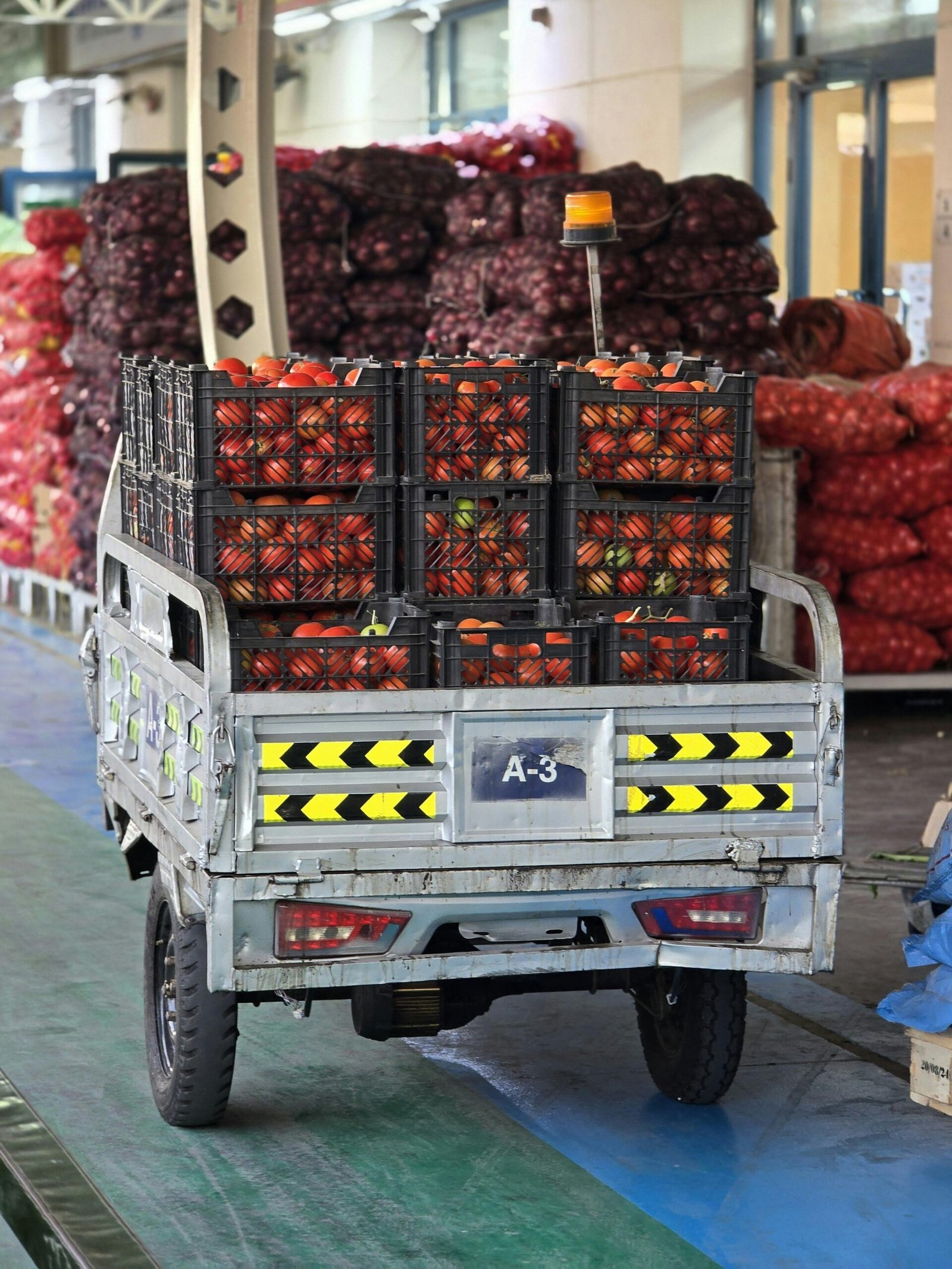 A small truck loaded with fresh tomatoes at a bustling market in Dubai.