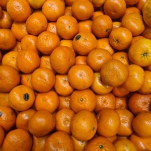 Vibrant fresh oranges piled up on a market stall, showcasing their bright color and texture.
